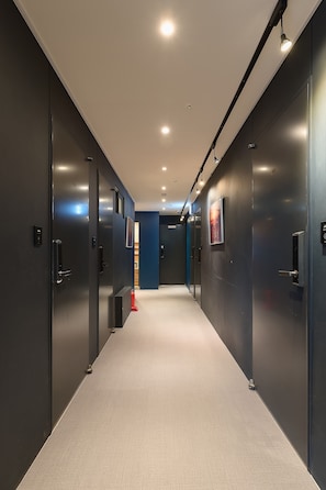 A modern hallway with dark walls, recessed lighting, and a carpeted floor.