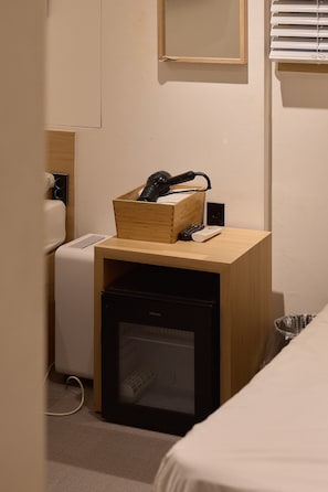 A compact hotel room with a wooden desk, a small black refrigerator, a white heater, and a wall-mounted mirror. - Artravel Myeongdong (Seoul)
