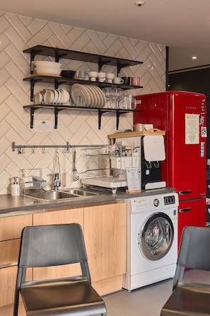 A kitchen with a coffee machine, a red refrigerator, a washing machine, and a herringbone-patterned wall. - Artravel Myeongdong (Seoul)