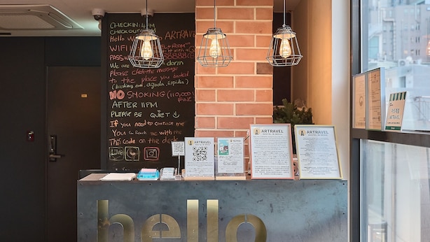 Een receptiebalie met een 'hello'-bord, een prikbord met informatie en hangende pendellampen.