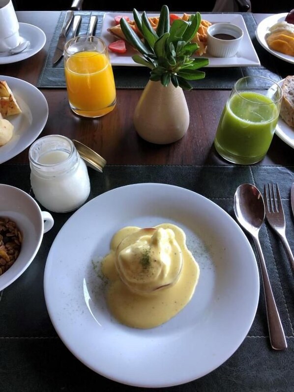 A dining table with a plate of food, a glass of orange juice, a green smoothie, and a small bowl of sauce. - B Hotel Brasilia (Brasília)