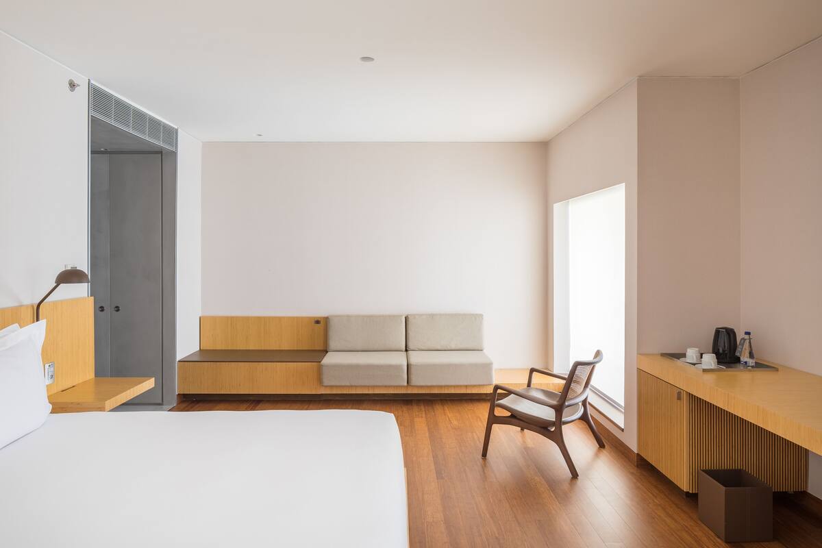 Een moderne hotelkamer met een bed, een houten bureau, een bank en een stoel.