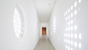 A modern, minimalist hallway with a light-colored floor and walls, featuring circular cutouts on the right wall and a large circular cutout on the left. - B Hotel Brasilia (Brasília)