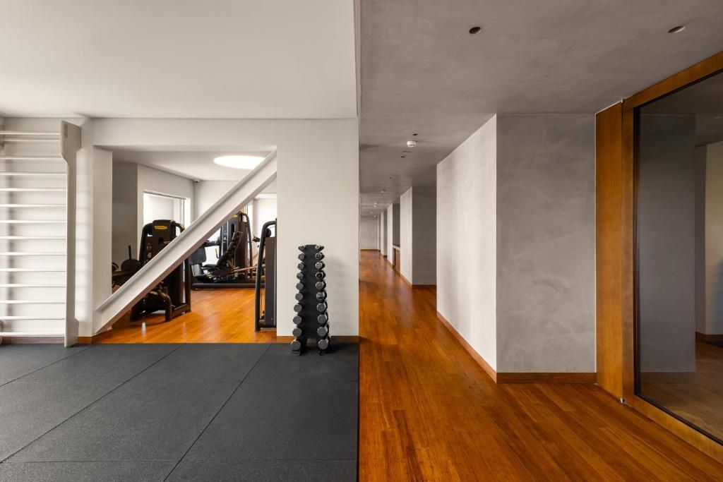 Un interior moderno con una escalera, una zona de gimnasio y un pasillo con suelo de madera.