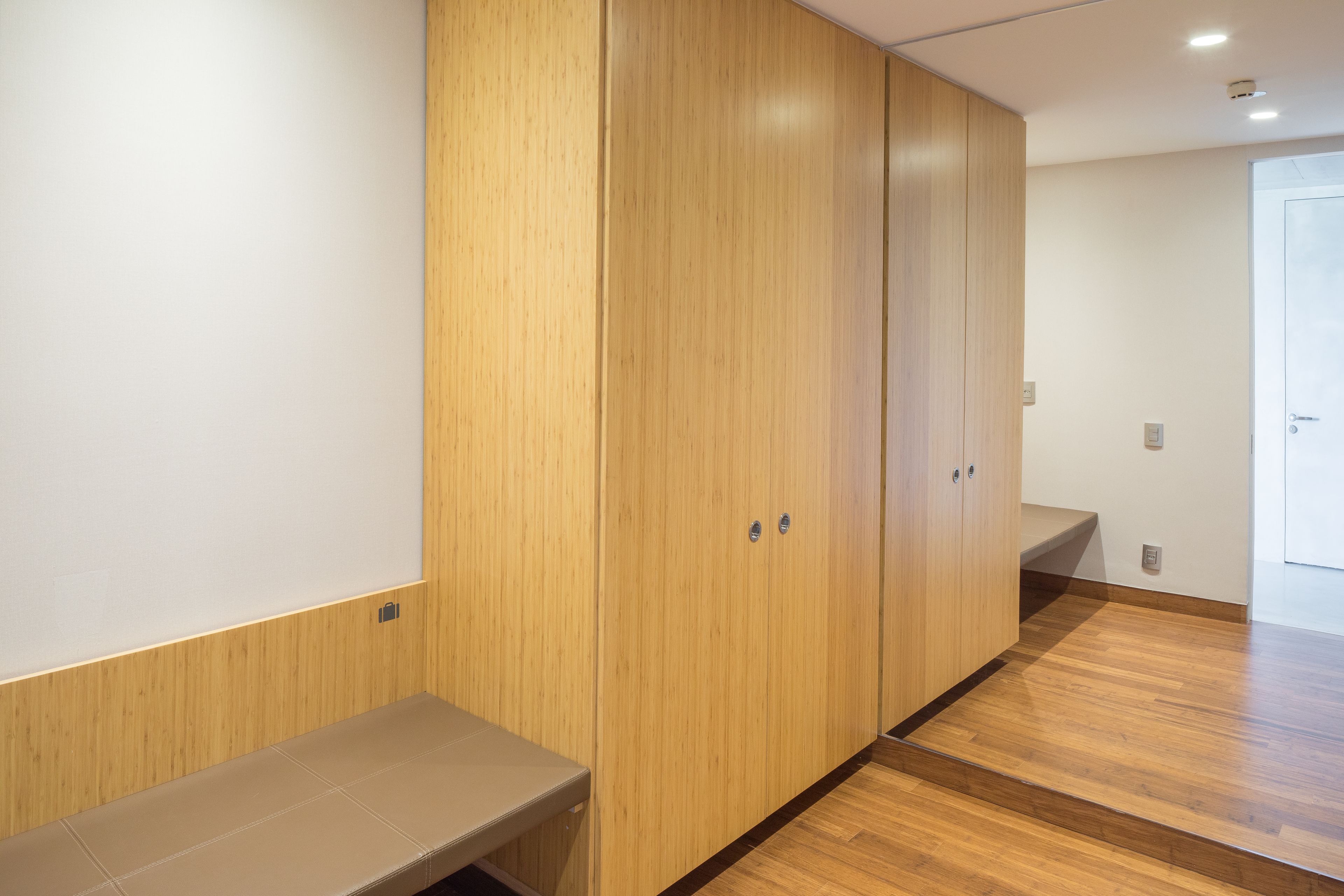 A modern room with wooden paneling, a bench, and a wooden floor.