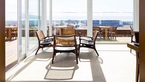 Een ruim balkon met grote ramen, houten meubels en uitzicht op de stad.