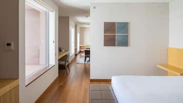 Une chambre d’hôtel moderne dotée d’une grande fenêtre, d’un banc en bois, d’un lit et d’un bureau avec une chaise.