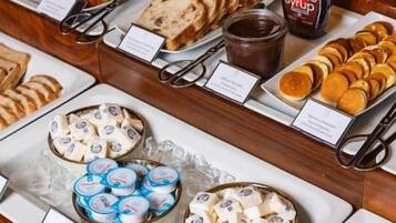 A breakfast buffet with various pastries, spreads, and dairy products.