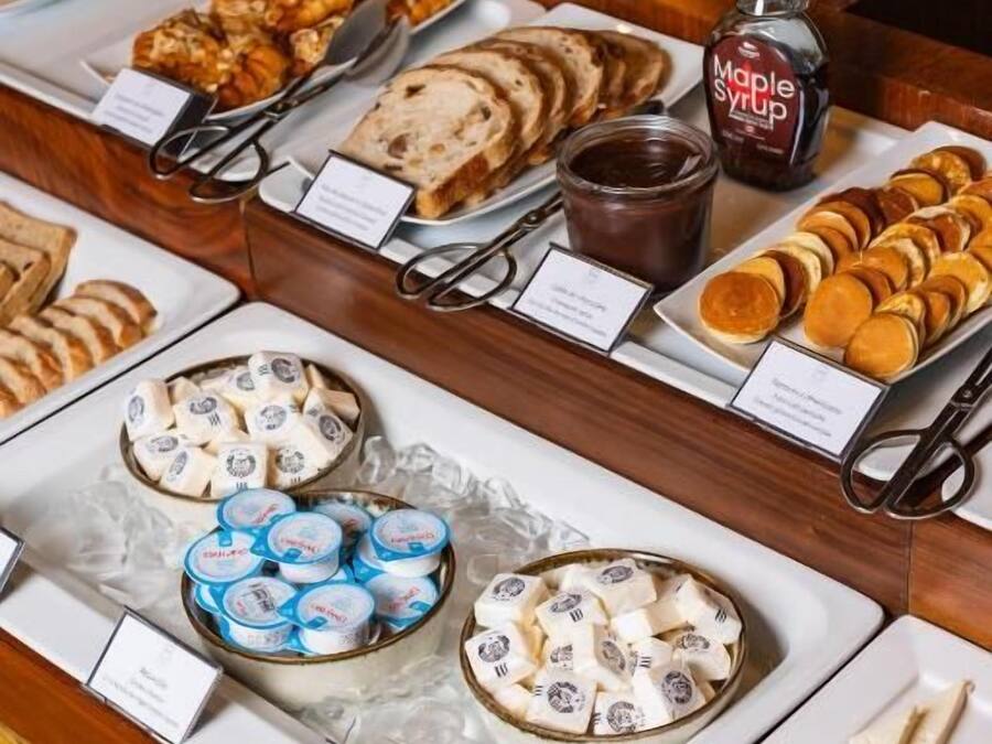 A breakfast buffet with various pastries, spreads, and dairy products.