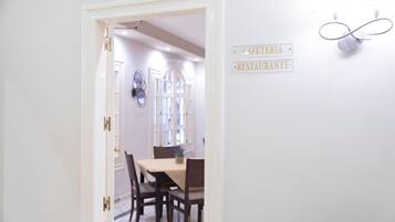 Un comedor con mesa y sillas, un letrero que indica cafetería y restaurante, y una lámpara de pared decorativa.