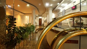 Vestíbulo de hotel con suelos de mármol, columnas y un mostrador de recepción.