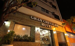 The exterior of the Gran Chevalier Hotel with a large sign above the entrance, a number '261' on the facade, and a circular emblem above the door. - Gran Chevalier Hotel (São Paulo)