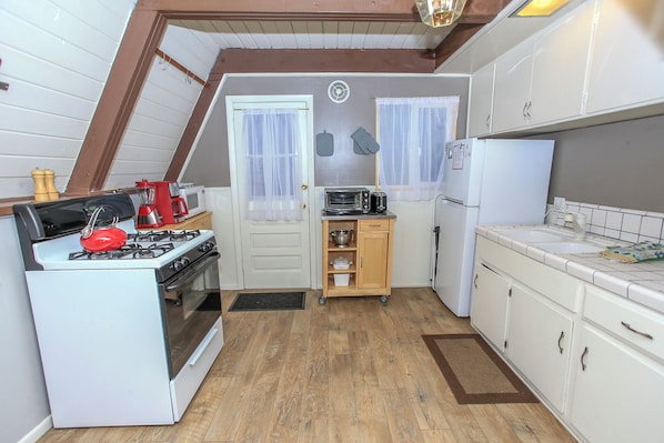 Una cocina compacta con estufa, microondas y refrigerador.