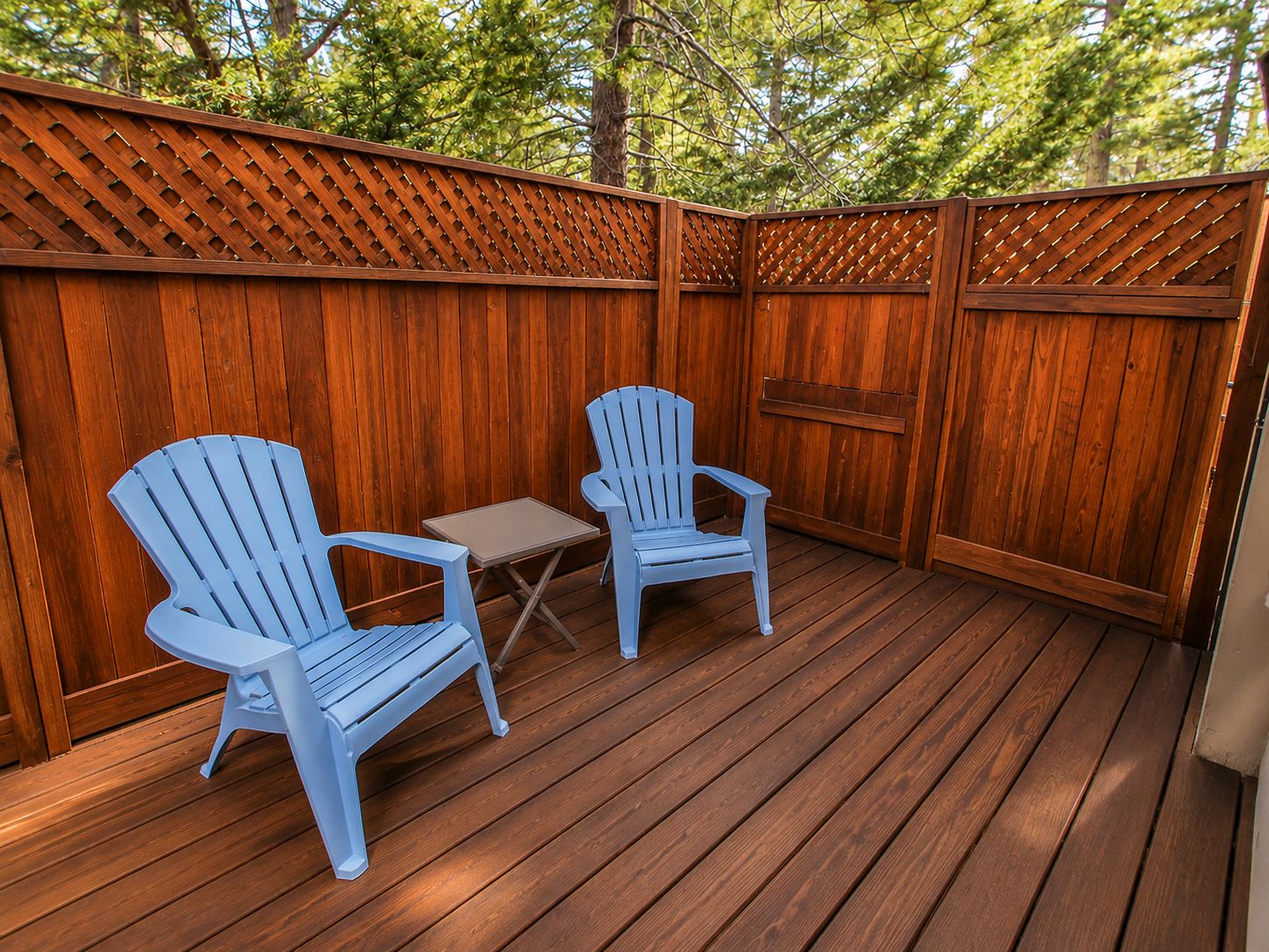 An outdoor deck with two Adirondack chairs and a small table.