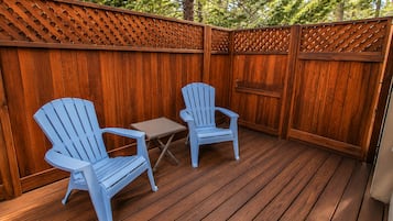 An outdoor deck with two Adirondack chairs and a small table.