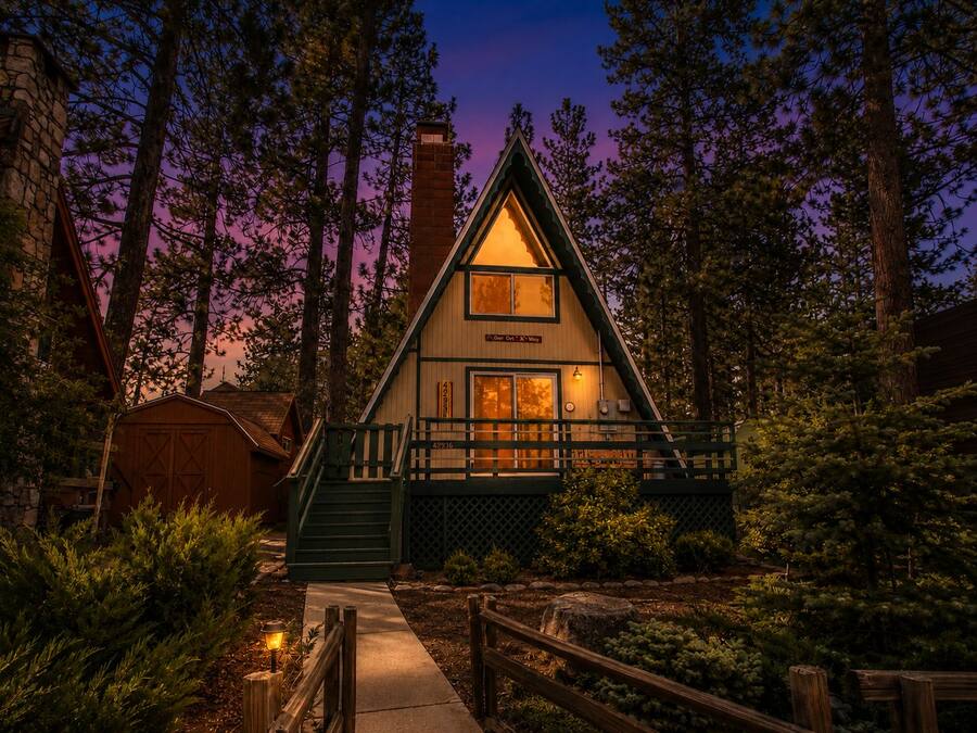 A cabin with a steeply pitched roof, a front porch, and a chimney.