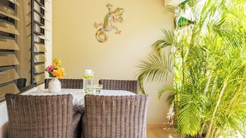 A dining area with wicker furniture, a table with a vase of flowers, and a wall-mounted lizard decoration.