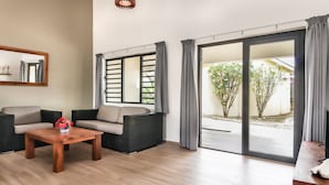 Una sala de estar moderna con un sofá, una mesa de centro y un amplio ventanal corredera que da a un espacio exterior.