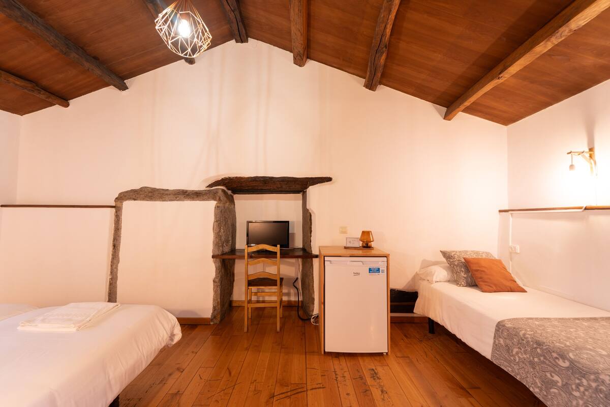 Ein gemütliches Zimmer mit zwei Betten, einem Schreibtisch mit Computer und einem kleinen Kühlschrank.