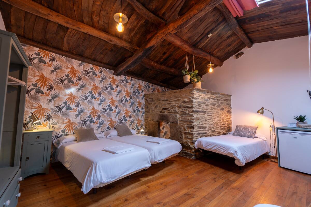 Ein Zimmer mit zwei Betten, Holzboden, einer Steinwand und einer rustikalen Decke.