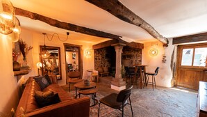 Un intérieur rustique avec un sol en pierre, des poutres en bois, un canapé en cuir et une cheminée en pierre.