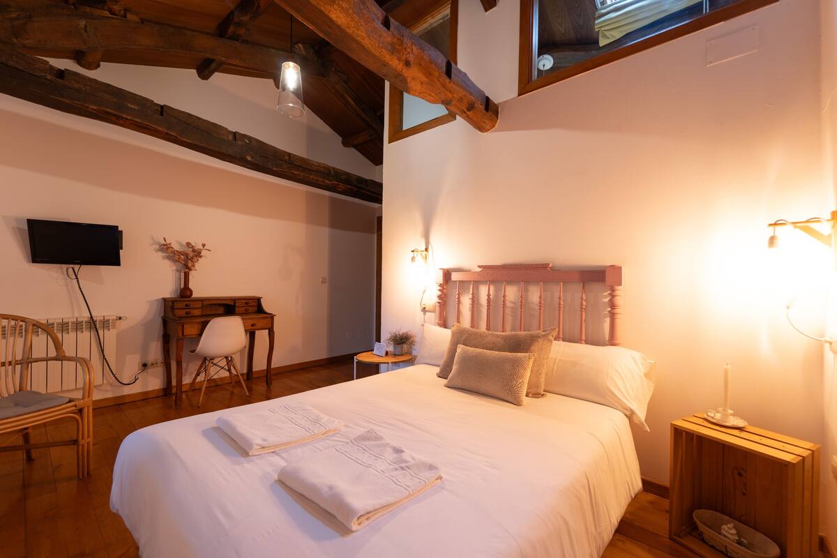 Ein Schlafzimmer mit einem großen Bett, einem Holzkopfteil, Nachttischen, einem Schreibtisch und einem Sessel.