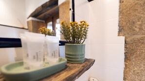 Un plan de travail de cuisine avec un pot vert contenant des fleurs jaunes, un plateau vert et un appareil électroménager blanc.