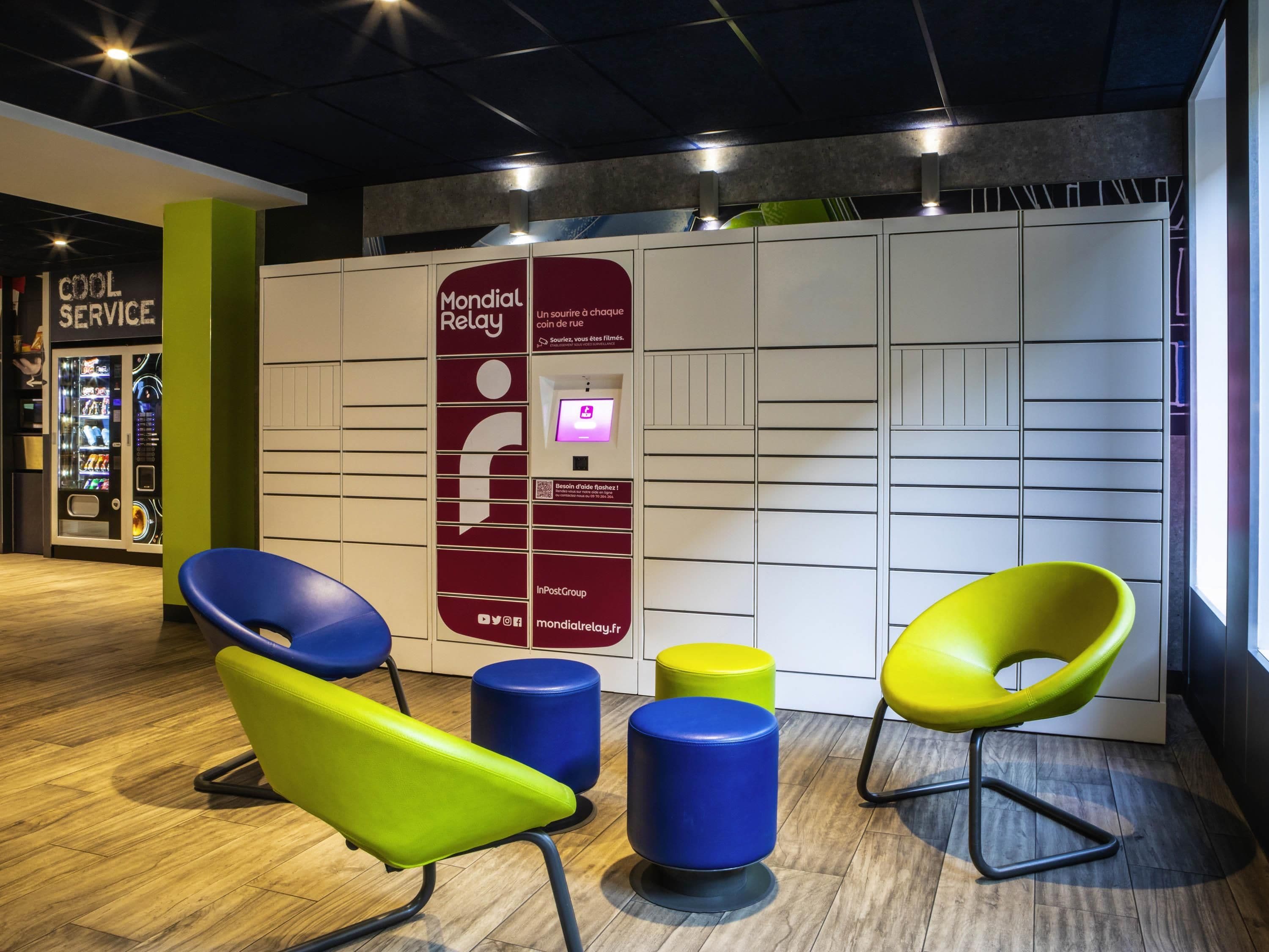 A modern waiting area with colorful chairs, a vending machine, and a service counter.