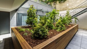 Un bâtiment moderne doté d’un jardin sur le toit, d’un escalier et offrant une vue sur les immeubles voisins.