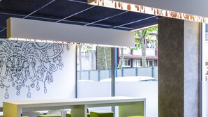 Ein modernes Café mit grün-weißen Sitzgelegenheiten, einem großen Fenster und einem Wandbild.