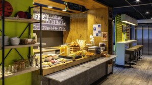Un espace buffet proposant divers plats, un menu écrit à la craie et des tabourets de bar.