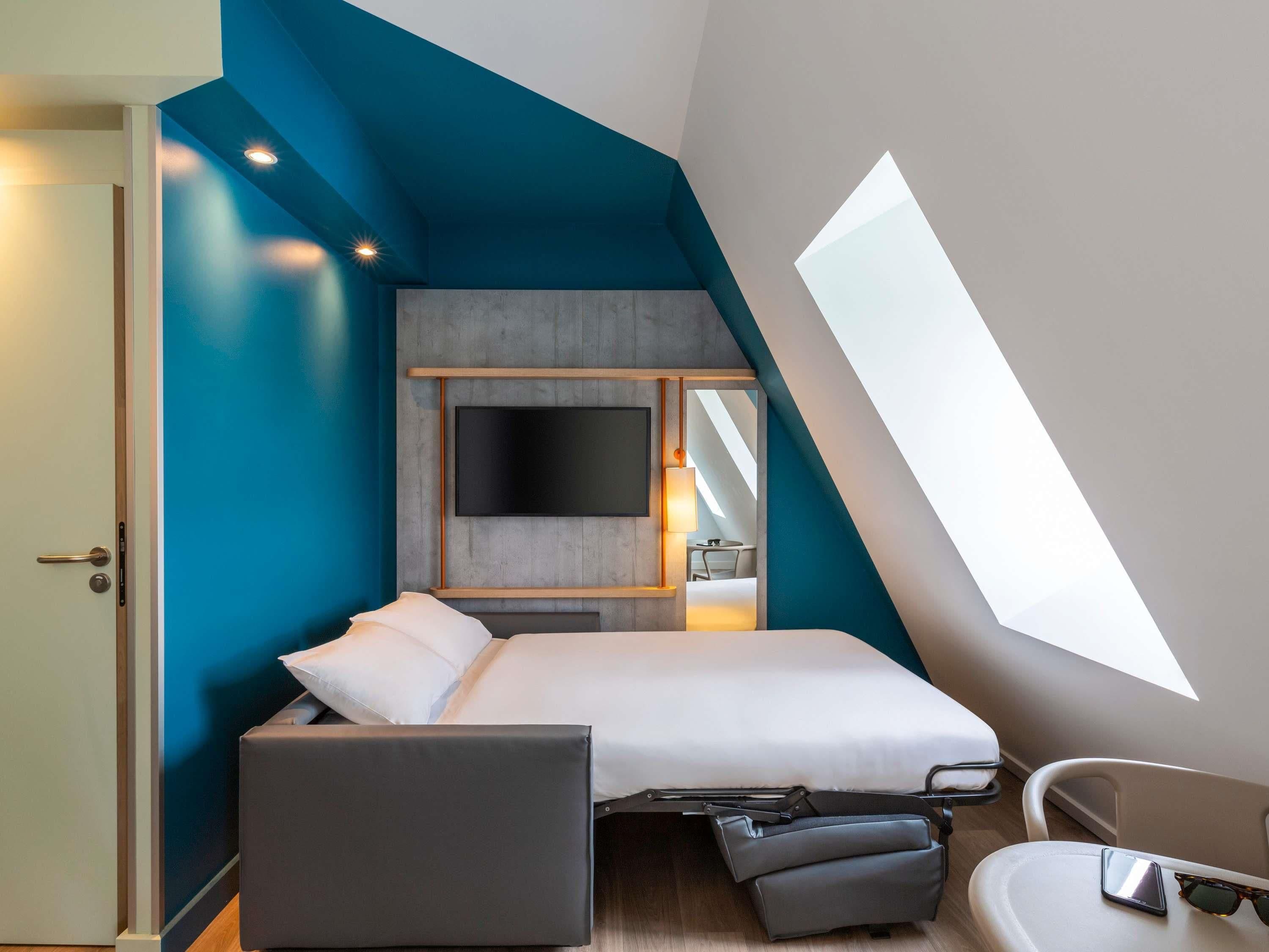 Een moderne slaapkamer met een bed, bureau en stoel.