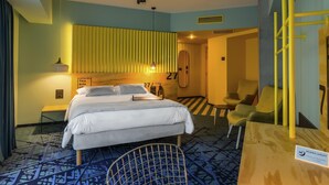 A hotel room with a bed, bedside tables, a mirror, a chair, and a small table.