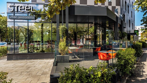 A modern building with a glass facade, labeled "Steel urban gastronomy."
