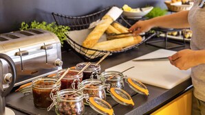 A kitchen counter with a toaster, a basket of bread, and jars of preserves.
