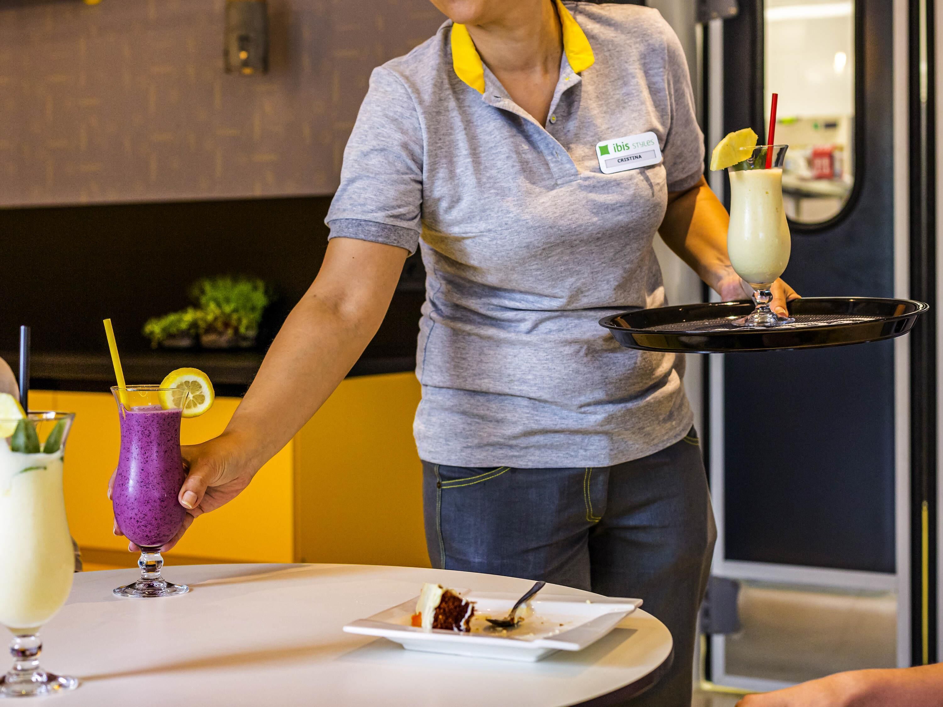 A person serving drinks and a dessert at a table.