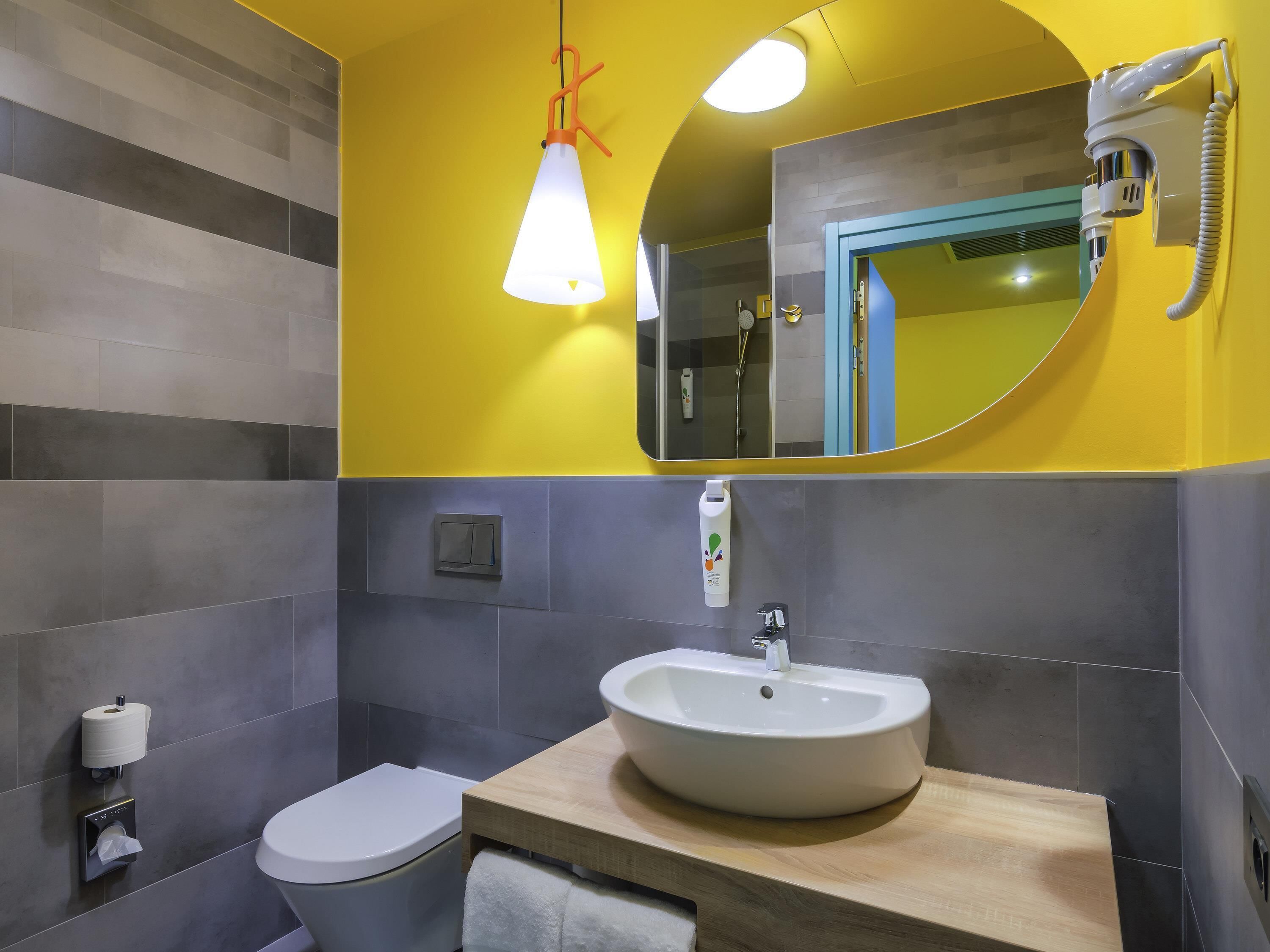 A bathroom with a toilet, sink, mirror, and a towel rack.