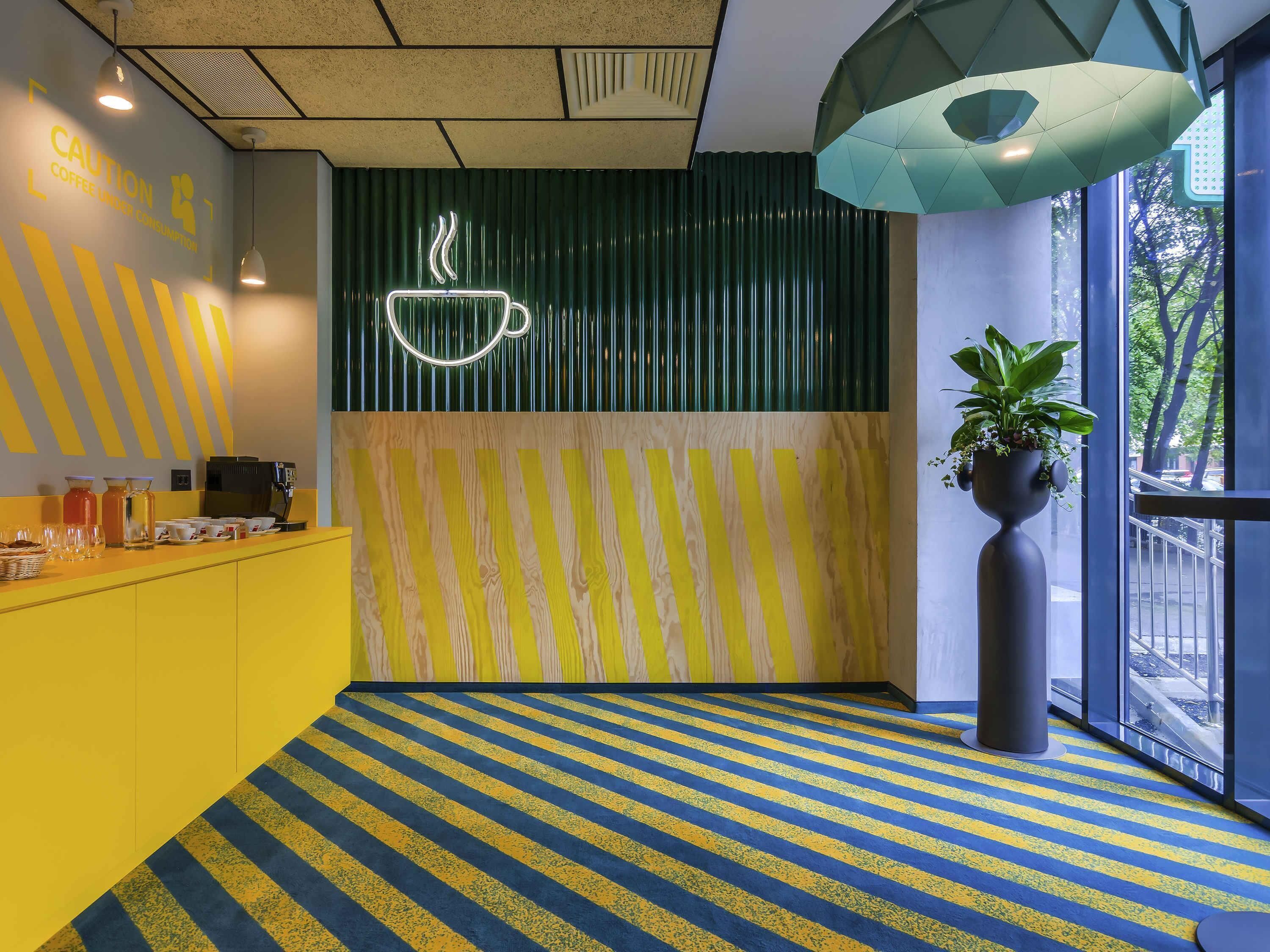 A modern interior with a striped floor, a coffee station, and a large window.