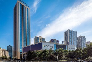 A modern building with a prominent 'Encore' sign, surrounded by other high-rise buildings and a clear blue sky. - Ramada Encore Chongqing Yubei (Chongqing)