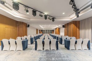 A conference room with rows of tables and chairs, equipped with overhead lighting and a stage. - Ramada Encore Chongqing Yubei (Chongqing)
