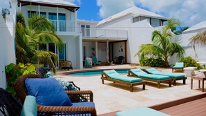 Um resort com piscina, espreguiçadeiras e um terraço coberto.