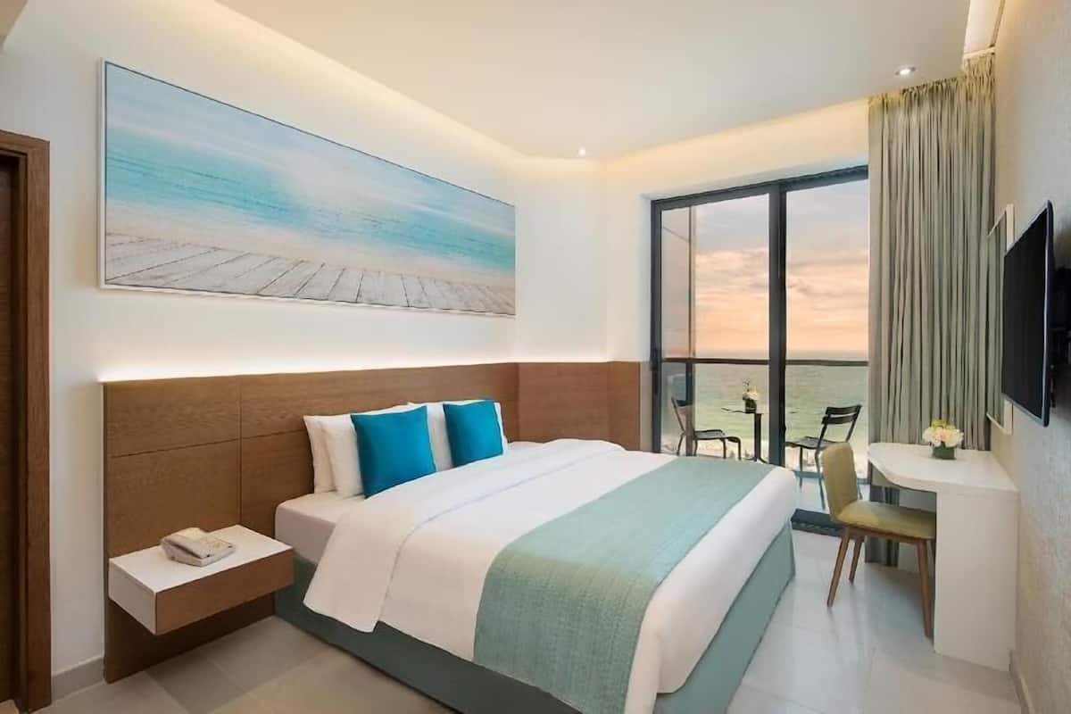 Een hotelkamer met een bed, een bureau, een stoel, een televisie en een groot raam met uitzicht.