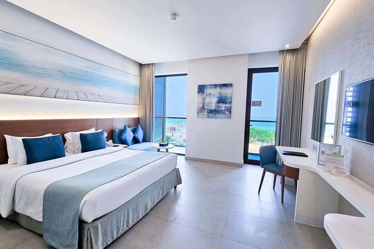 Een moderne hotelkamer met een groot bed, een bureau en uitzicht op het groen.