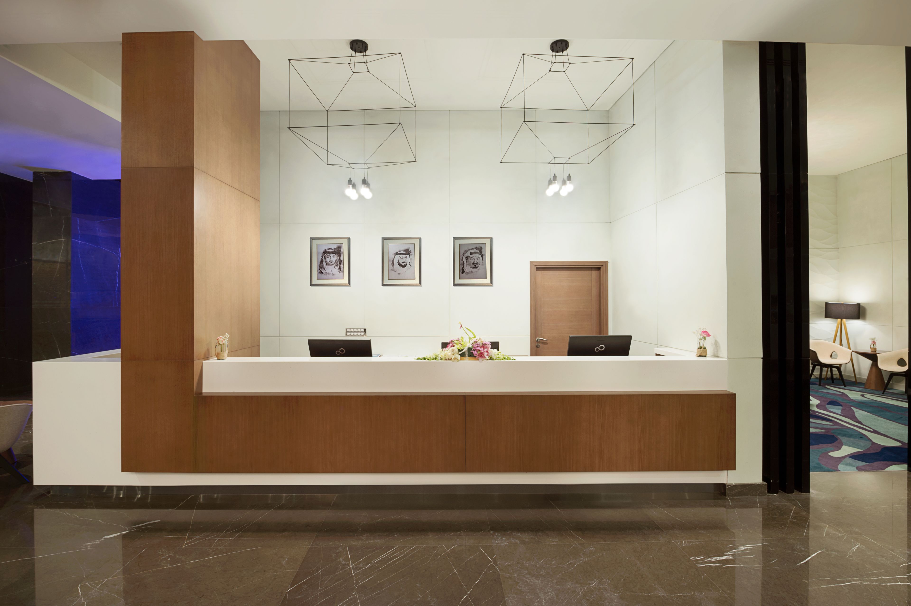 A modern reception desk with two computers, framed artwork on the wall, and a wooden accent wall.