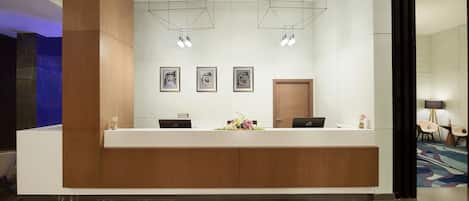 A modern reception desk with two computers, framed artwork on the wall, and a wooden accent wall.