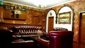 A room with a leather sofa, wooden cabinets, a chandelier, and a painting on the wall.