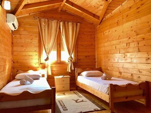 Een houten kamer met twee bedden, een nachtkastje en een raam met gordijnen.