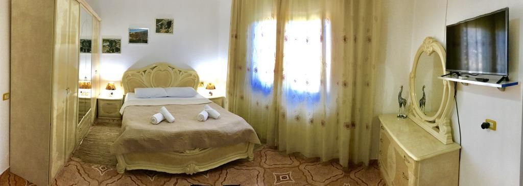 A hotel room with a bed, a TV, a dresser, and a mirror.