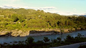 A river with a rocky riverbank and a forested hillside in the background.