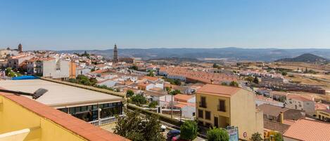 A town with a prominent clock tower, terraced houses, and a hilly landscape in the background.